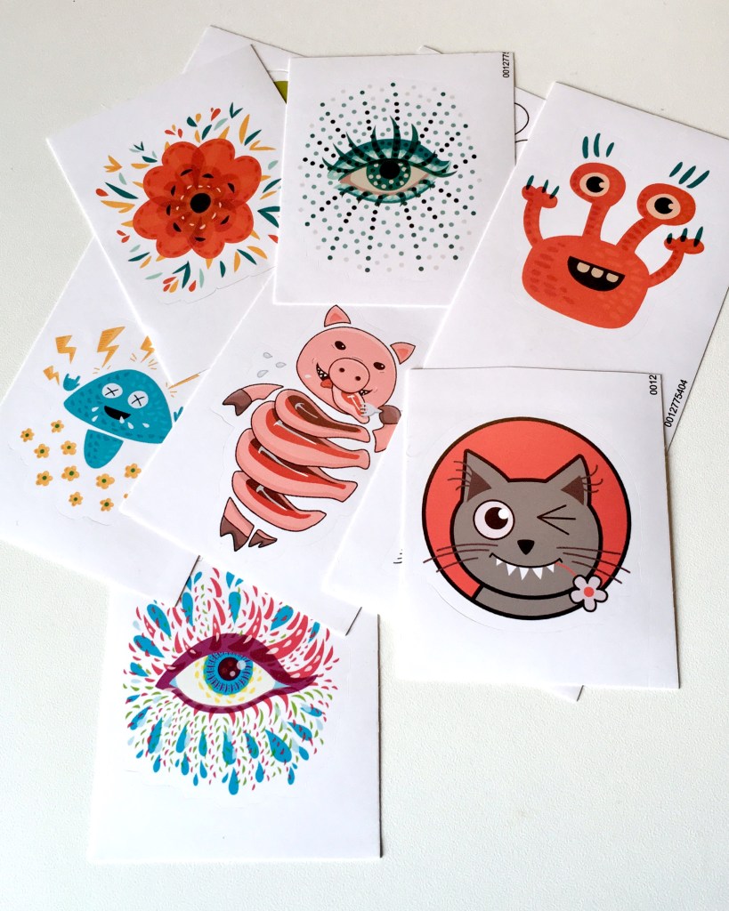 Art stickers which I bought from my Redbubble store - heavy metal mushroom, orange flower, orange monster, pig cute in steaks, winking kitty cat and psychedelic blue eye.