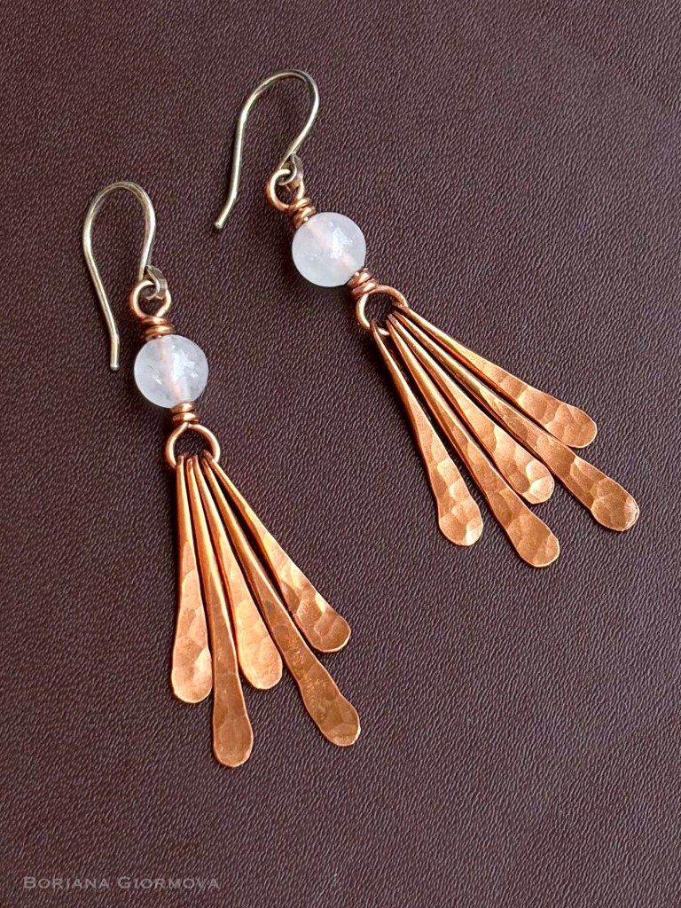 hammered copper moonstone earrings with silver ear wires and fringe effect shot on dark brown leather