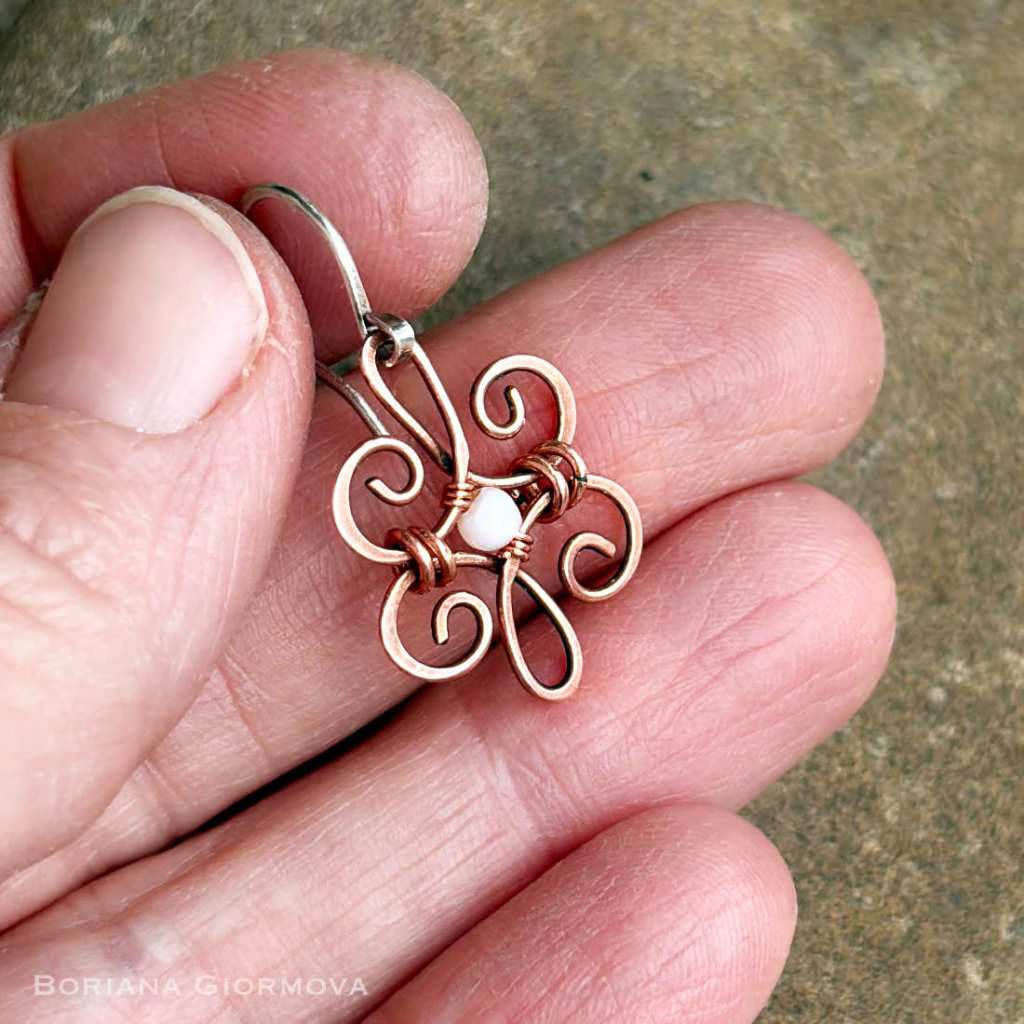 copper earring with mother of pearl bead held in hand