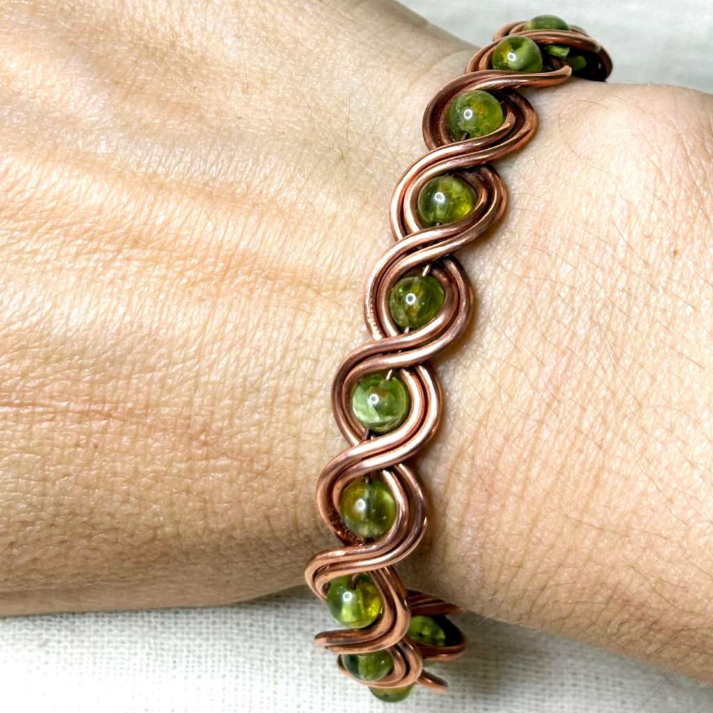 handmade copper cuff bracelet with green stones on hand